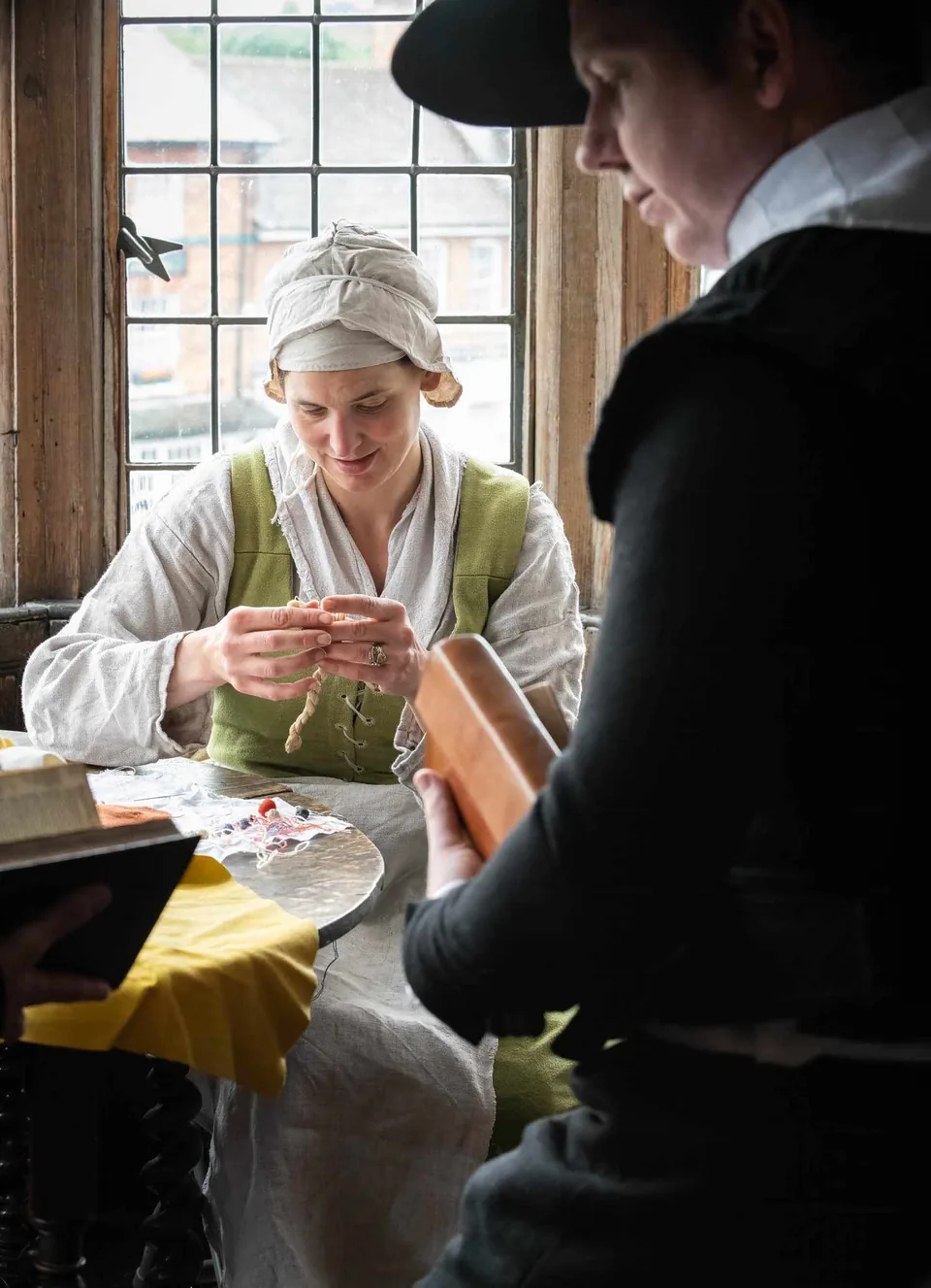A volunteer supporting a costumed textile demonstration
