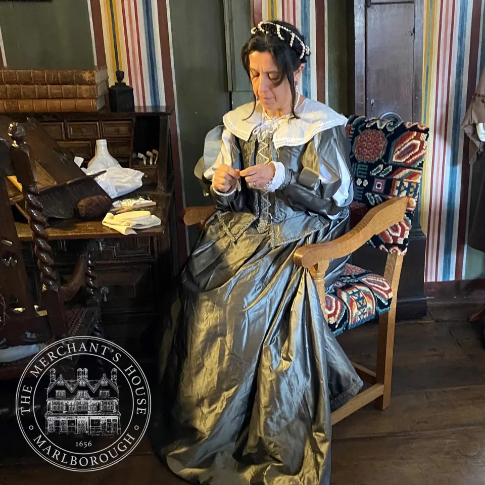 A costumed historical interpreter in a panelled room