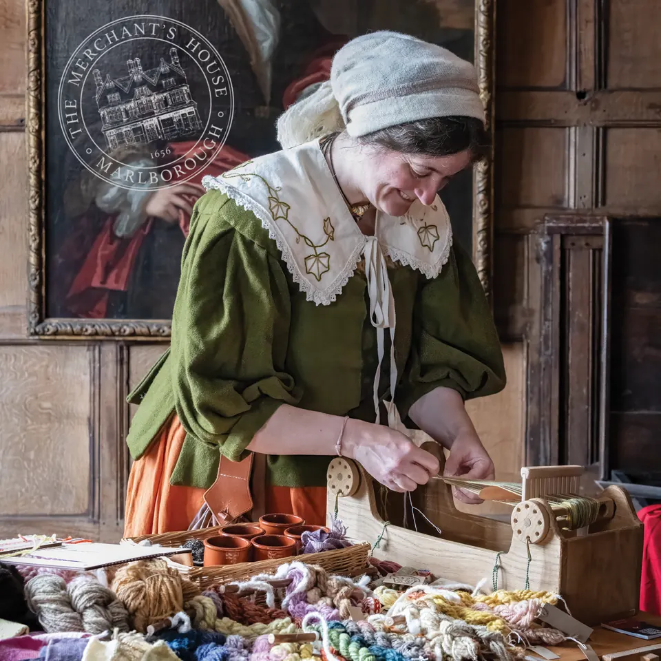 A costumed interpreter demonstrating household objects at a table